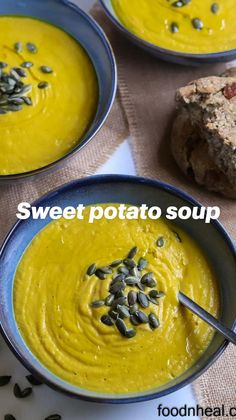 three bowls filled with yellow soup and topped with pumpkin seeds next to a piece of bread