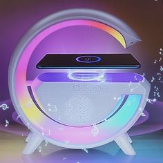 an electronic device sitting on top of a white speaker with colorful lights around it's edges