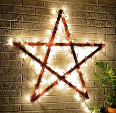 a lighted star on a brick wall next to a potted plant