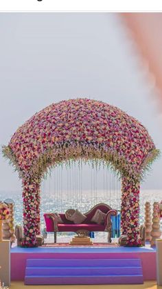 an outdoor ceremony setup on the beach with pink and white flowers in the middle,