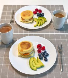 two white plates topped with pancakes and fruit next to a cup of coffee on a table