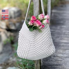 a white purse with pink flowers hanging from it's side on a wooden post