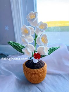 a crocheted flower pot with white flowers in it