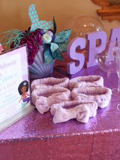 a table topped with purple and white items next to a sign that says welcome to someone special