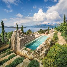 an outdoor swimming pool surrounded by greenery and stone steps leading up to the water