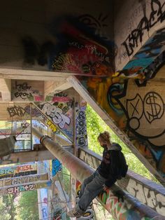 a man climbing up the side of a bridge covered in graffitti and spray paint