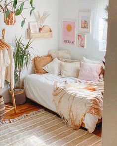 a bedroom with a bed, plants and pictures on the wall