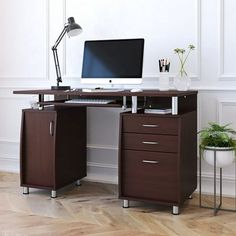 a desk with a computer on it in an empty room next to a potted plant