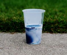 a blue and white cup sitting on top of a cement slab next to grass in the background