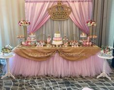 a table topped with lots of cakes and desserts next to a wall covered in pink drapes