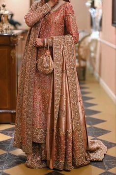 a woman in an orange and gold bridal gown holding her hand on her shoulder