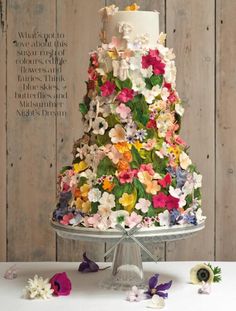 a multi - tiered cake decorated with flowers on a table in front of a wooden wall