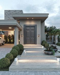 the front entrance to a house with steps leading up to it and potted plants on either side