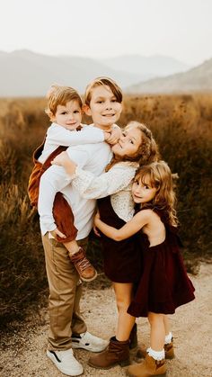 a group of children hugging each other on a dirt road