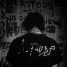 the back of a man's shirt with graffiti on it in front of a wall