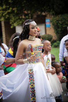 a woman in a white dress standing next to other people