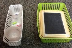 two plastic containers sitting on top of a floor next to a chalkboard and container