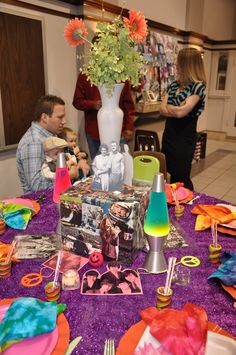 a table topped with pictures and vases filled with flowers on top of a purple table cloth