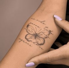 a woman's arm with a butterfly tattoo on it and words written in cursive writing