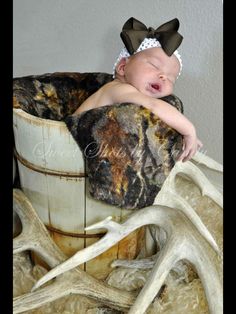 a baby is sleeping in a bucket with antlers