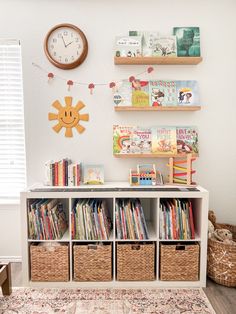 there is a book shelf with many books on it and a clock above the shelves