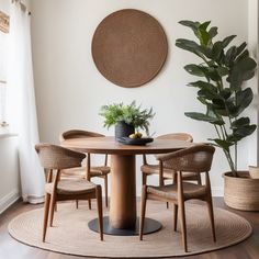 a round table with four chairs and a potted plant on it in front of a white wall