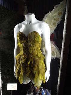 a mannequin wearing a yellow dress with feathers on it's chest and wings