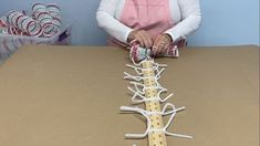 a woman is working on a tree made out of tape measures and candy canes