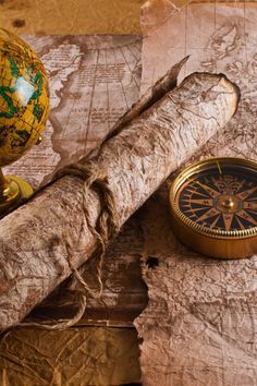 an old map, compass, and wooden stick on top of a piece of paper