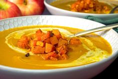 two bowls filled with soup next to apples