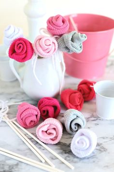 crocheted flowers are sitting on the table next to knitting needles and yarn balls