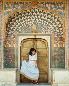 a woman standing in front of an ornate doorway