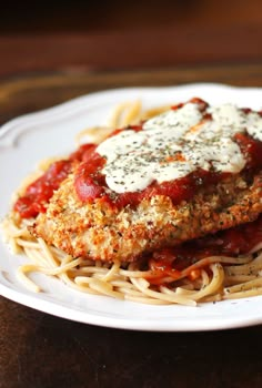 two pieces of chicken parmesan on top of spaghetti