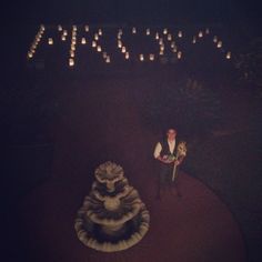 a man standing next to a fountain with candles in the background