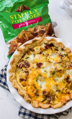 a cheesy quiche sits on a plate next to a bag of potato chips