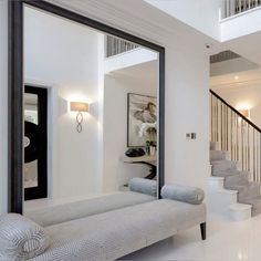 a living room filled with furniture next to a stair case in front of a mirror