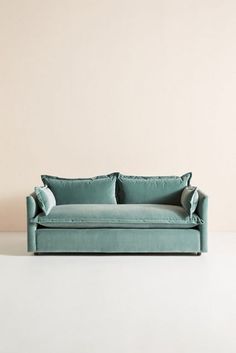 a blue couch sitting on top of a white floor next to a wall with a light colored background