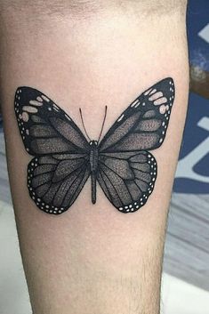 a black and white butterfly tattoo on the right leg, with dots around it's wings