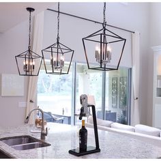 three lights hanging from the ceiling over a kitchen island with granite counter top and sink