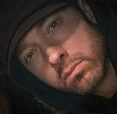 a close up of a man wearing a hoodie and looking at the camera with an intense look on his face