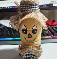 a paper cup with a scarecrow face on it sitting in front of a computer keyboard