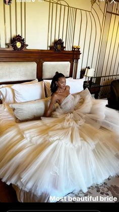 a woman laying on top of a bed in a white dress with ruffled skirt