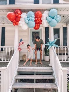 balloons and stars are on the front porch of a house with stairs leading up to it