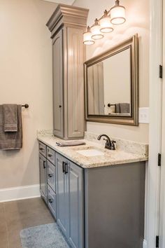 a bathroom with gray cabinets and marble counter tops