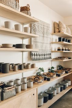 the shelves are filled with bowls, plates and other items in baskets on top of them