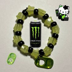 a green bracelet with black beads and a can of monster energy on the side next to it