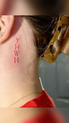 a woman with a red tattoo on her neck and behind her ear that reads yhw