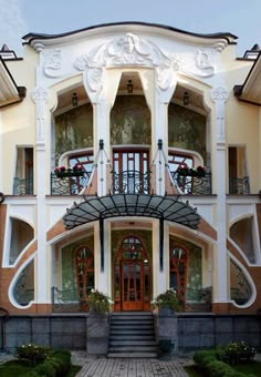 a large white building with many windows and balconies on the top floor, along with steps leading up to it