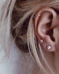 a close up of a person with ear piercings on their ears and behind the ear