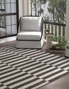 a white chair sitting on top of a black and white striped rug next to a window